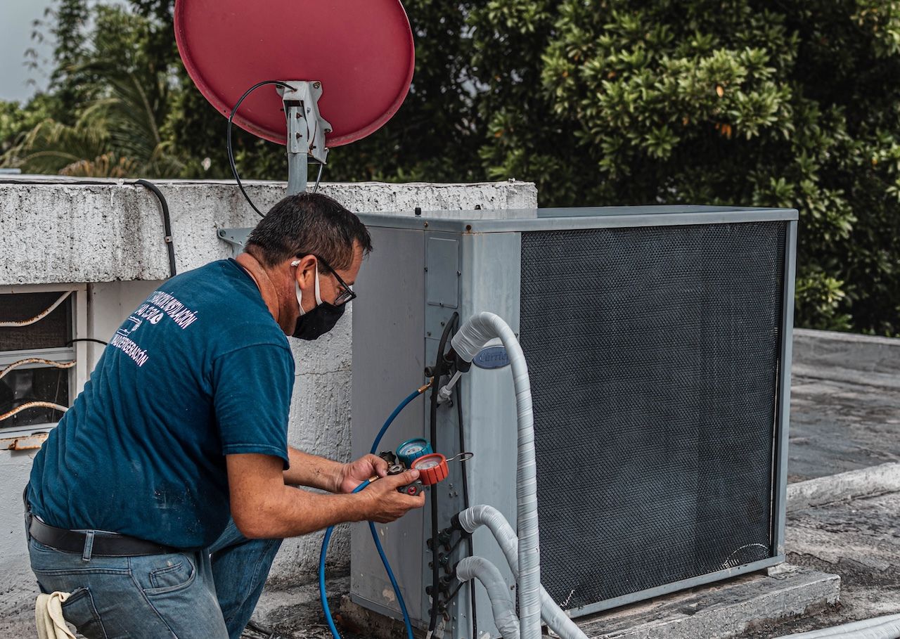 Tecnico al lavoro su un’unità esterna di climatizzazione installata in copertura